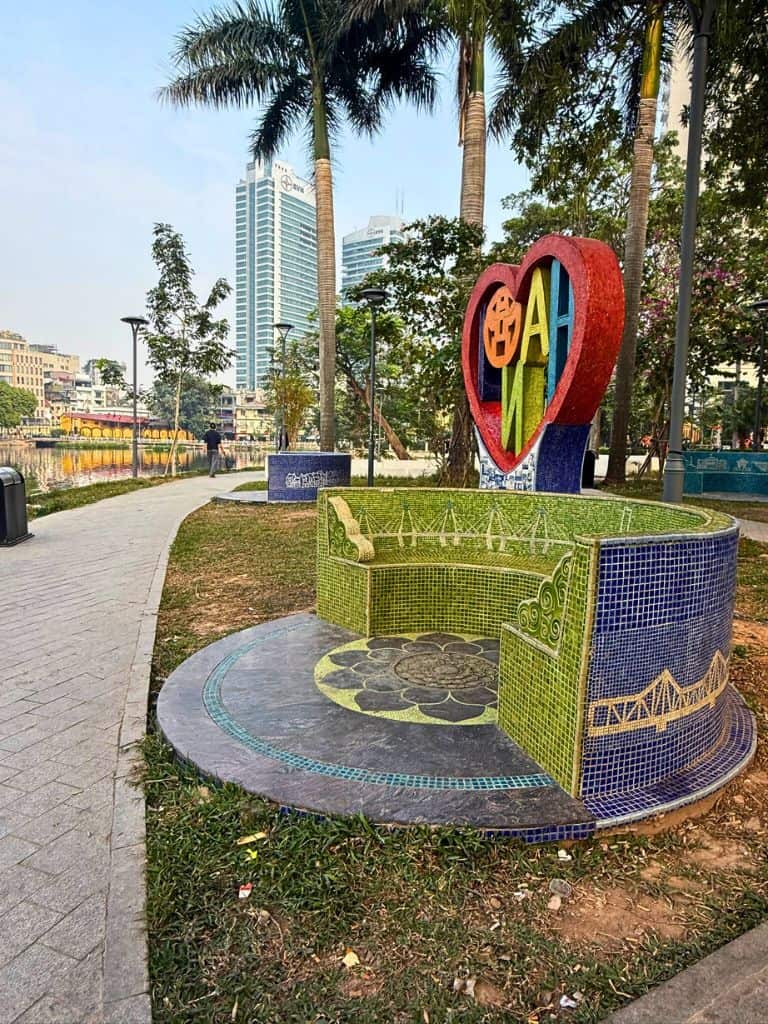 Heart Hanoi sign side view with tall buildings in the background