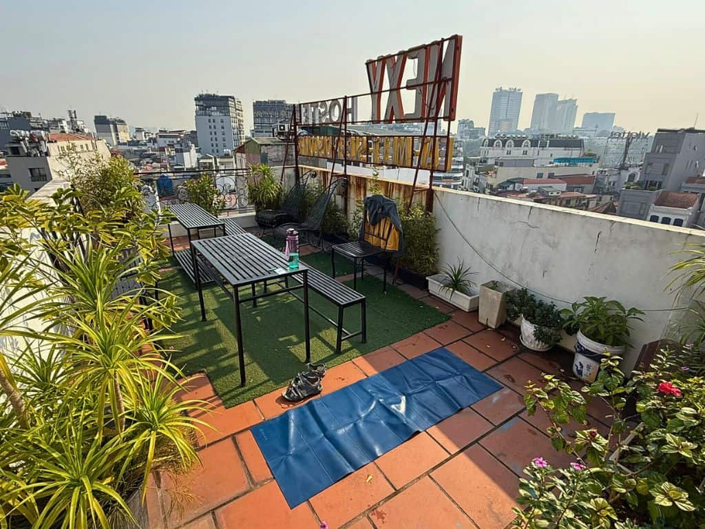 Rooftop of the hostel with a yoga mat laid out next to the chair and tables with plants nearby