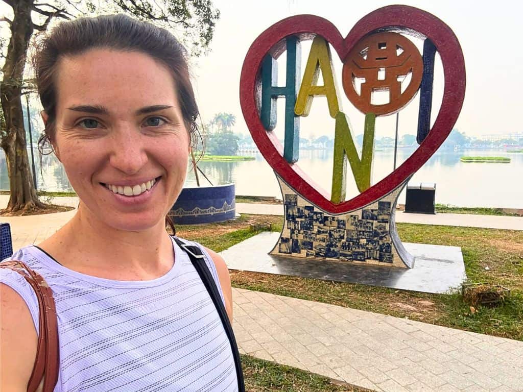 Heidi smiling in front of the Hanoi heart sign