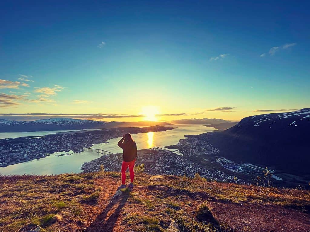 Heidi, the author, standing away from camera facing the view of Tromso and midnight sun.