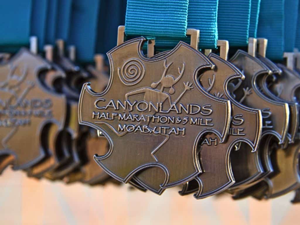 Up close photo of dozens of Canyonlands half marathon and 5 mile medals for Moab, Utah.