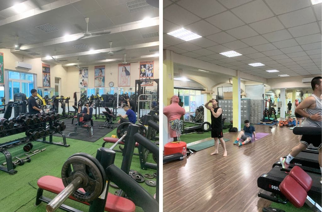 Two photos inside the X-Men Gym in Hanoi showing the bench press machines, benches, and dumbbell options. The second photo shows the space behind the treadmills for using mats and hitting a dummy. There are also lockers in the background.