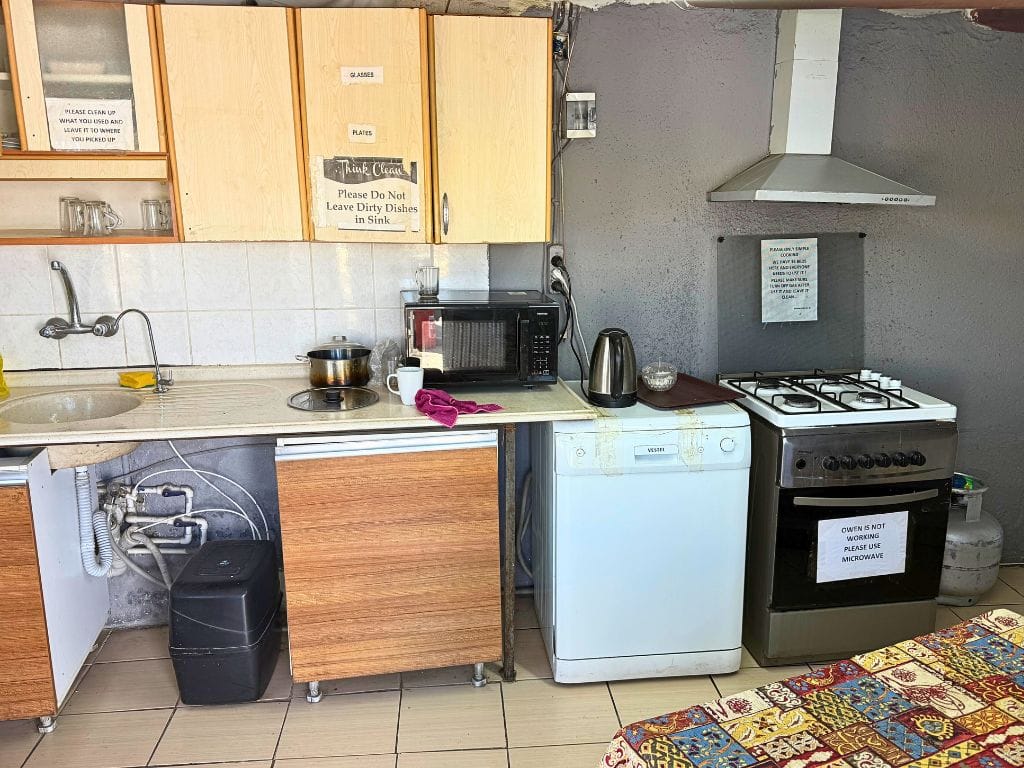 Hostel kitchen showing a sink, microwave, hot water kettle, stove, and oven