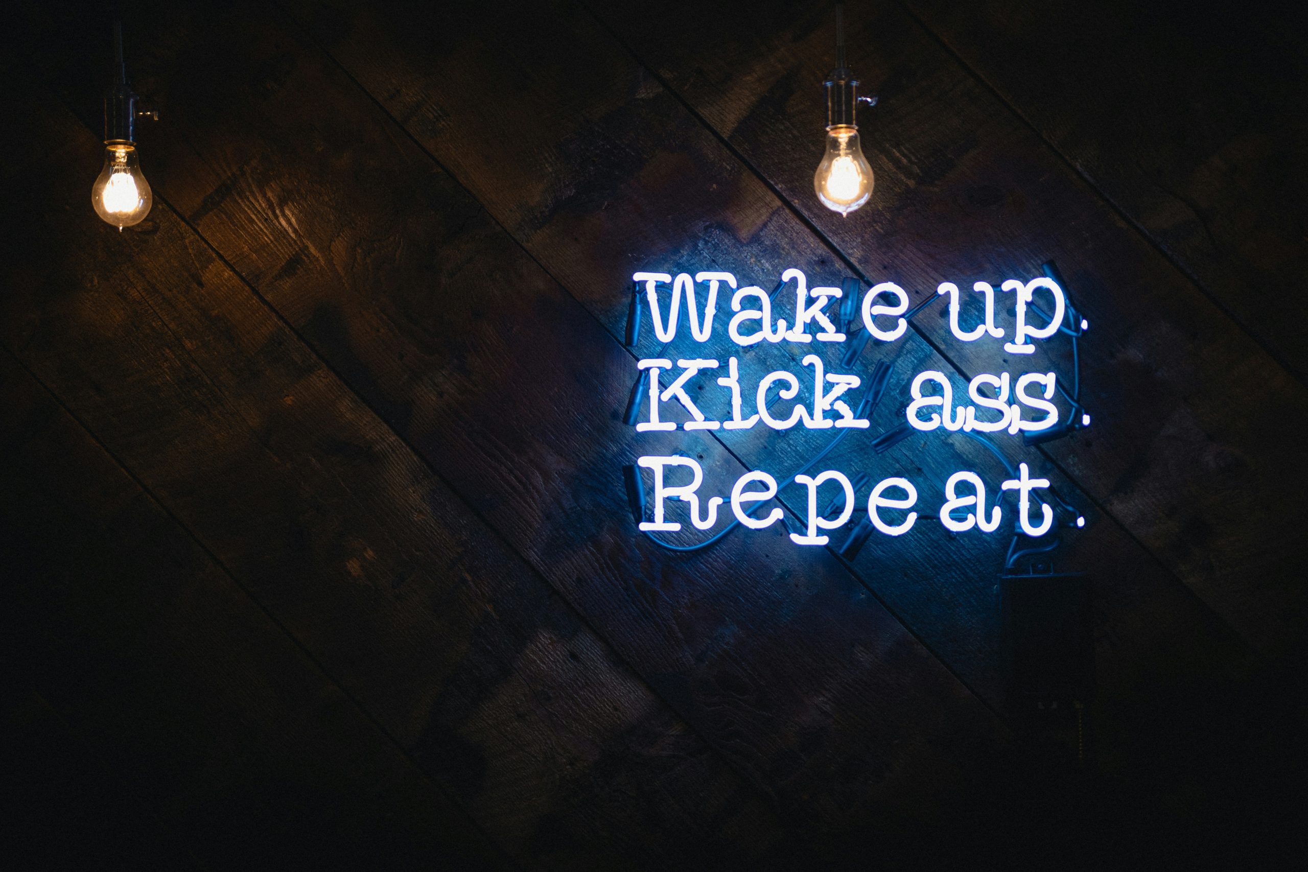 Neon sign stating: Wake up. Kick ass. Repeat.
