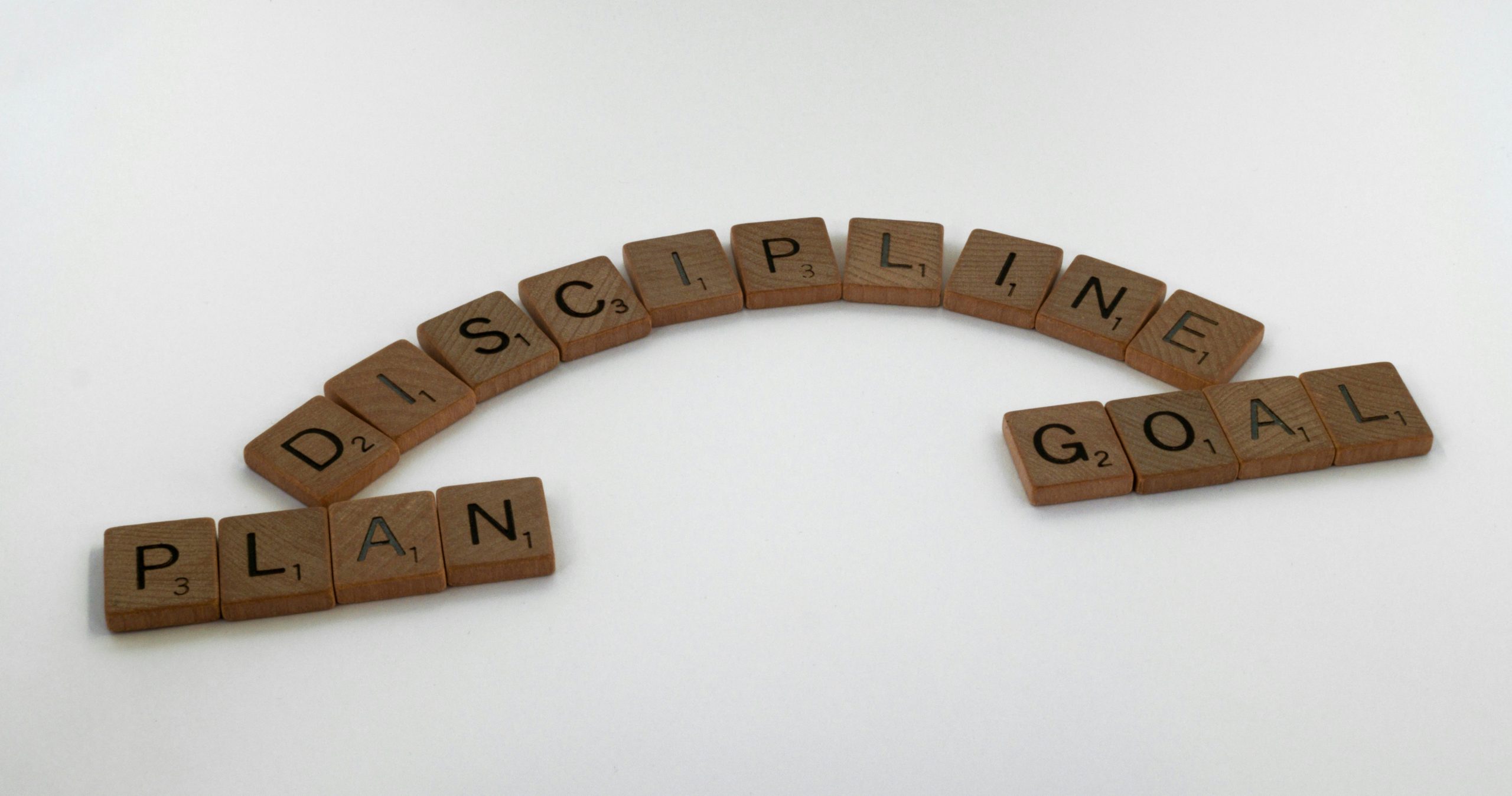 Scrabble tiles spelling the words: discipline, plan, goal.