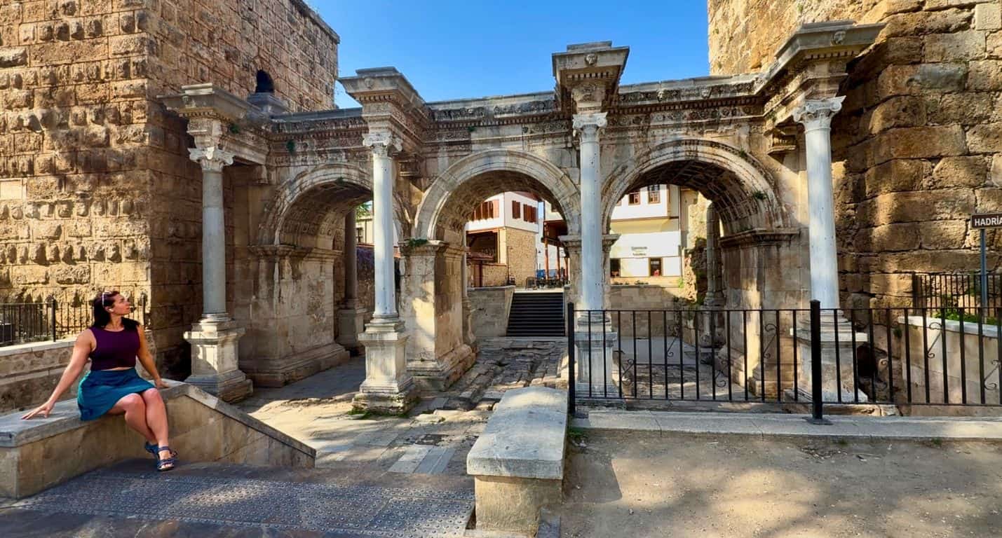 Wide view of traveler sitting and posing in front of Hadrian's Gate in Antalya, Turkiye