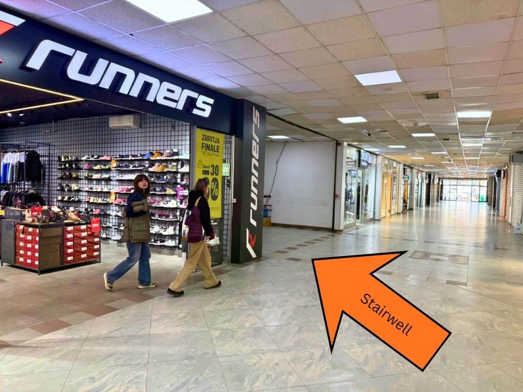 Orange arrow pointing to the staircase on the left of the hallway