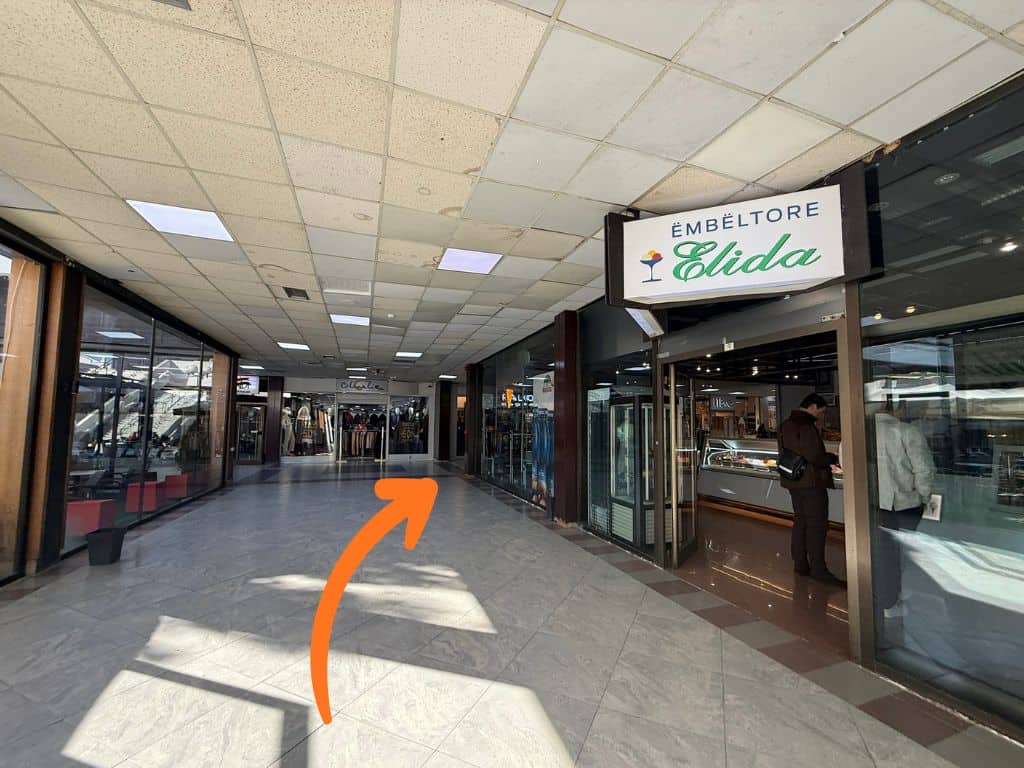 Interior shopping hallway with an orange arrow pointing to the corner after the Elida sweets shop